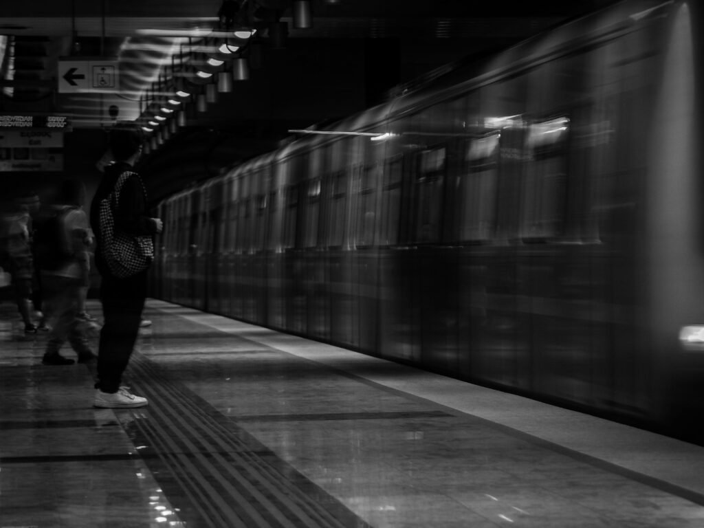 A monochrome capture of a subway train in motion at an underground station platform.